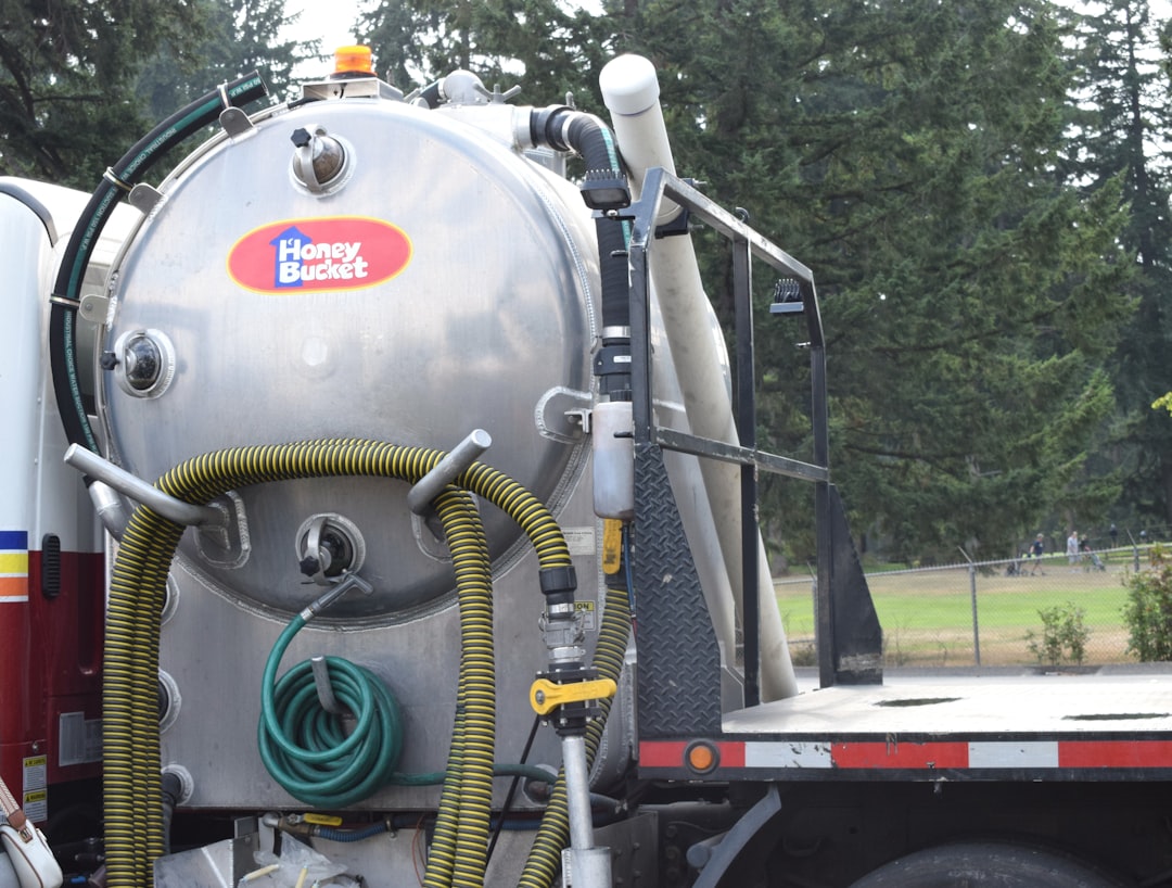 Silver vacuum truck tank with hoses and pipes